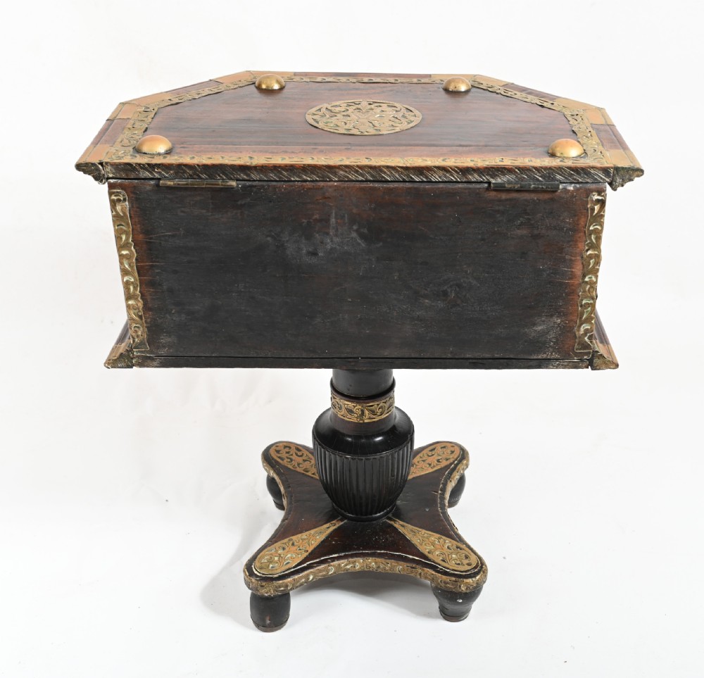 An antique dark wood Indian dowry casket decorated with intricate pierced brass straps and studs, supported on a turned central pedestal base. View XI