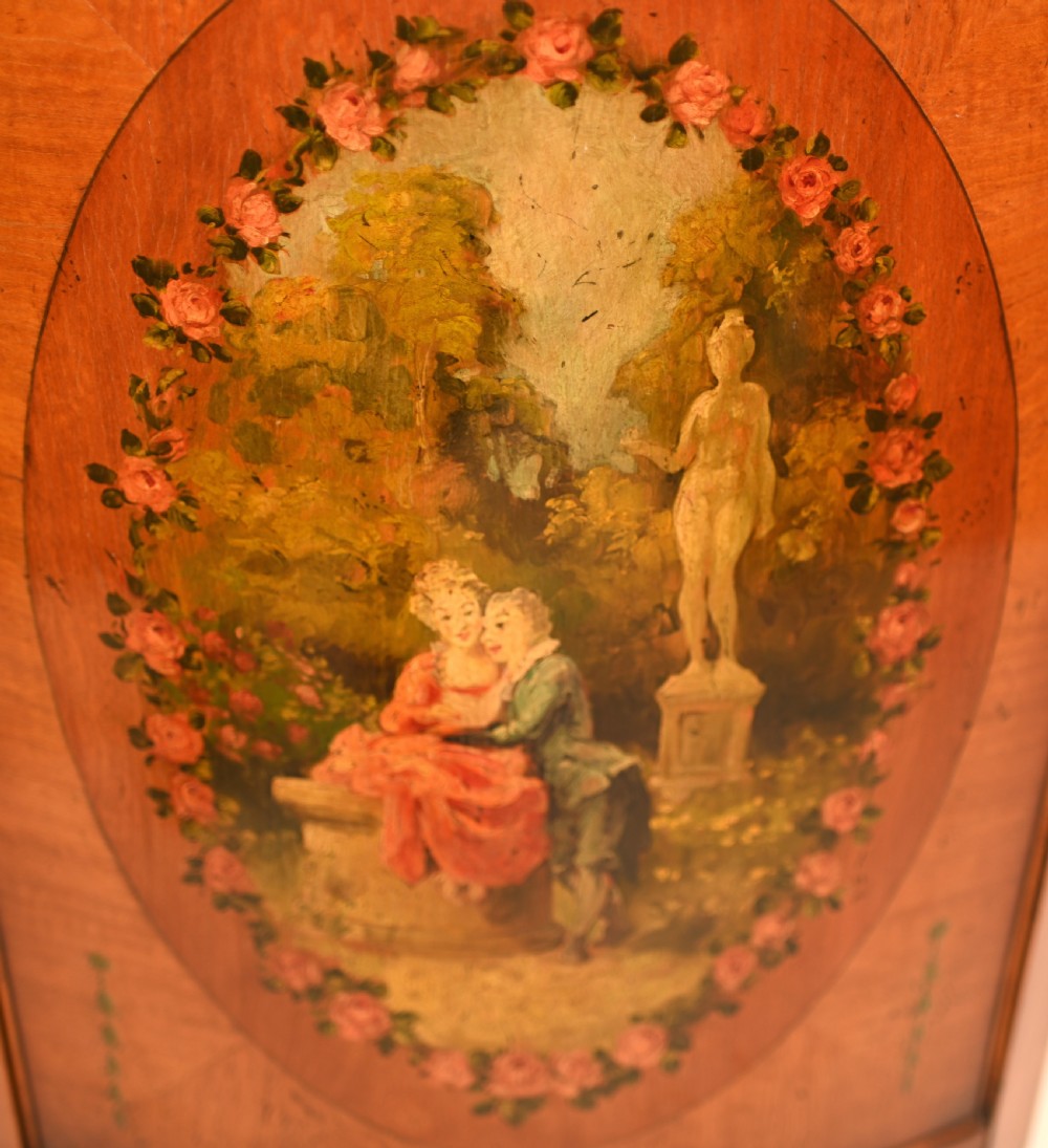 A semi-circular satinwood commode cabinet featuring three oval painted vignettes with classical figurative scenes and floral borders. View V