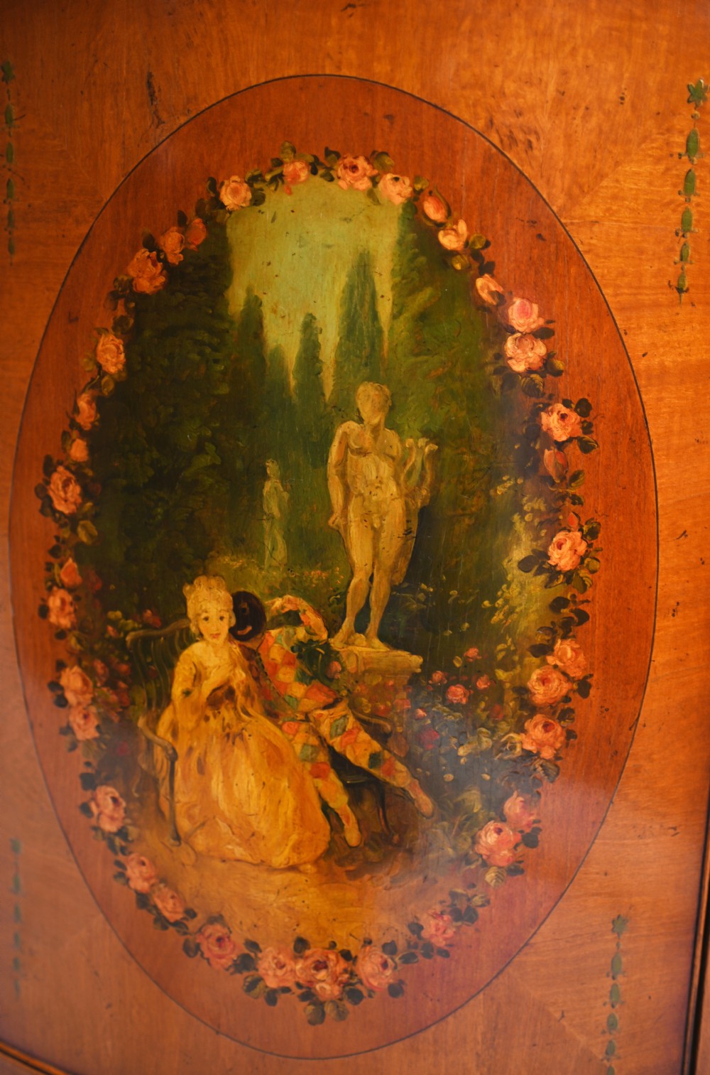 A semi-circular satinwood commode cabinet featuring three oval painted vignettes with classical figurative scenes and floral borders. View VII
