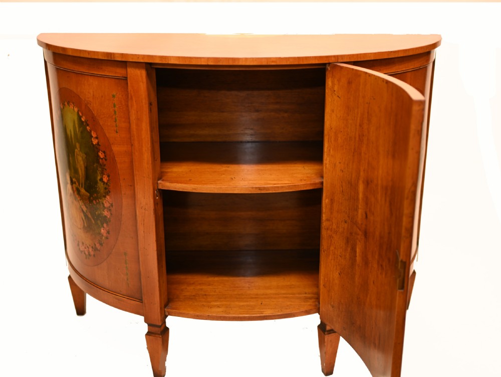 A semi-circular satinwood commode cabinet featuring three oval painted vignettes with classical figurative scenes and floral borders. View VIII
