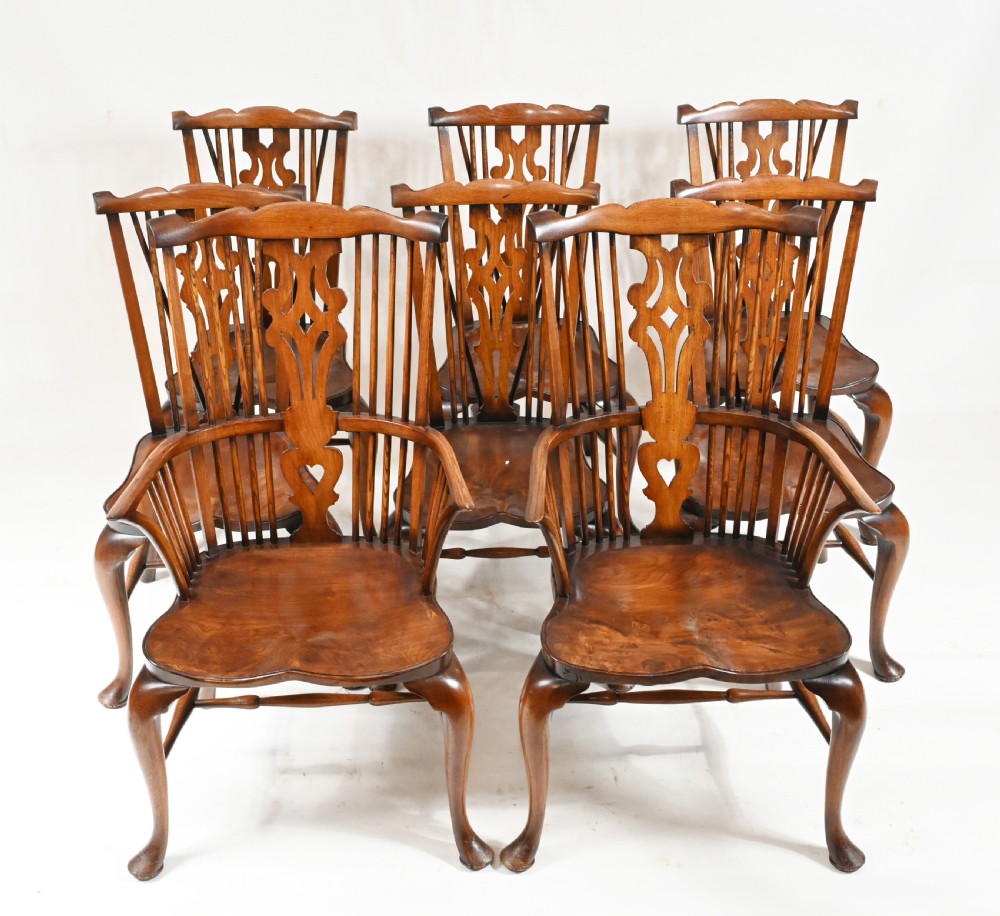 A set of eight yew wood Windsor dining chairs featuring pierced splats, saddle seats, and cabriole front legs.