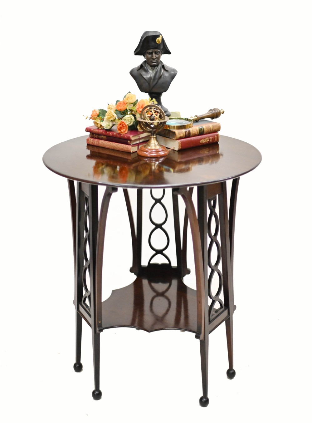 A late nineteenth-century dark mahogany occasional table featuring a circular top, pierced geometric fretwork legs, an undertier shelf, and ball feet.