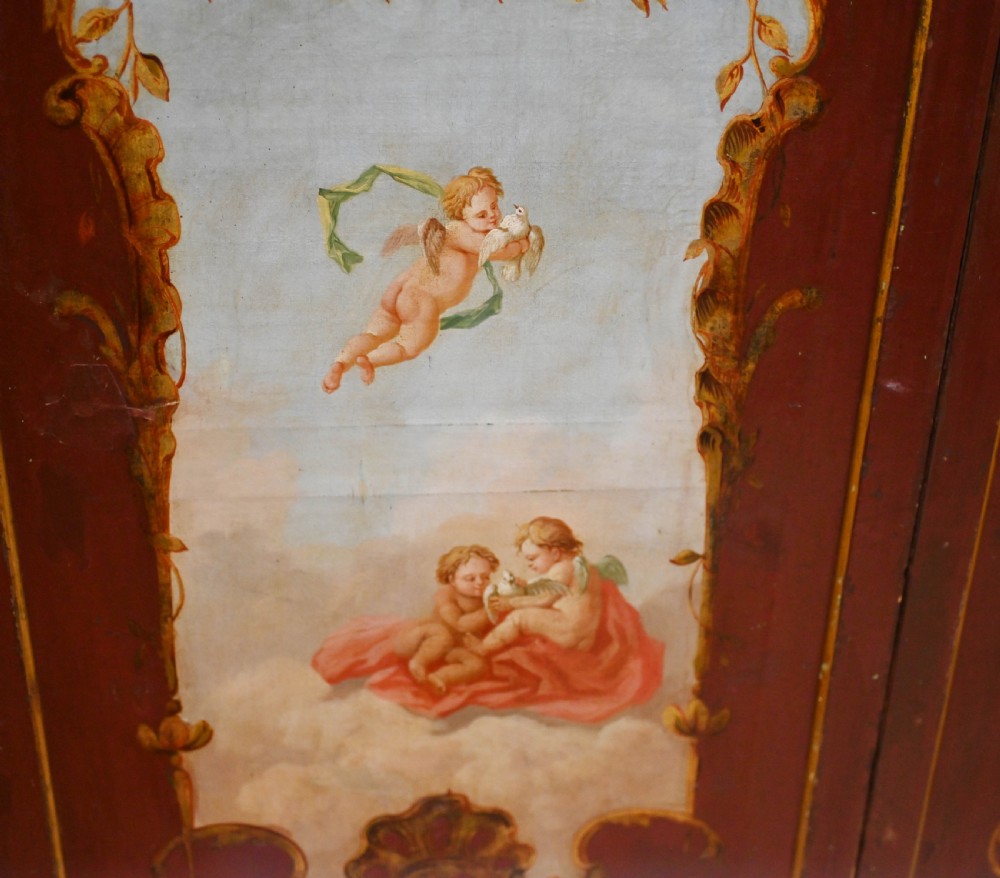 A red six-panel folding screen painted with classical figures, cherubs, and urns within gilded scrollwork borders. View II