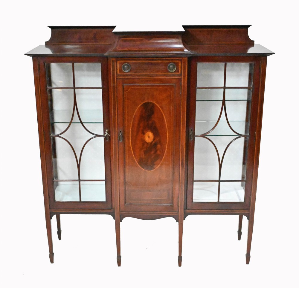 An Edwardian mahogany display cabinet featuring astragal glazed doors flanking a central inlaid cupboard door raised on square tapered legs.