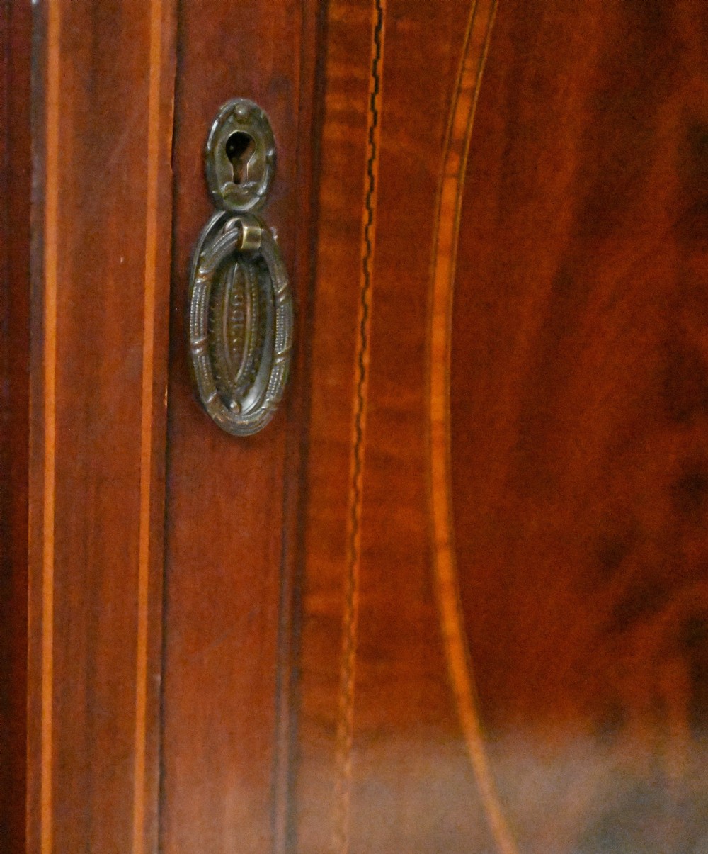 An Edwardian mahogany display cabinet featuring astragal glazed doors flanking a central inlaid cupboard door raised on square tapered legs. View IV