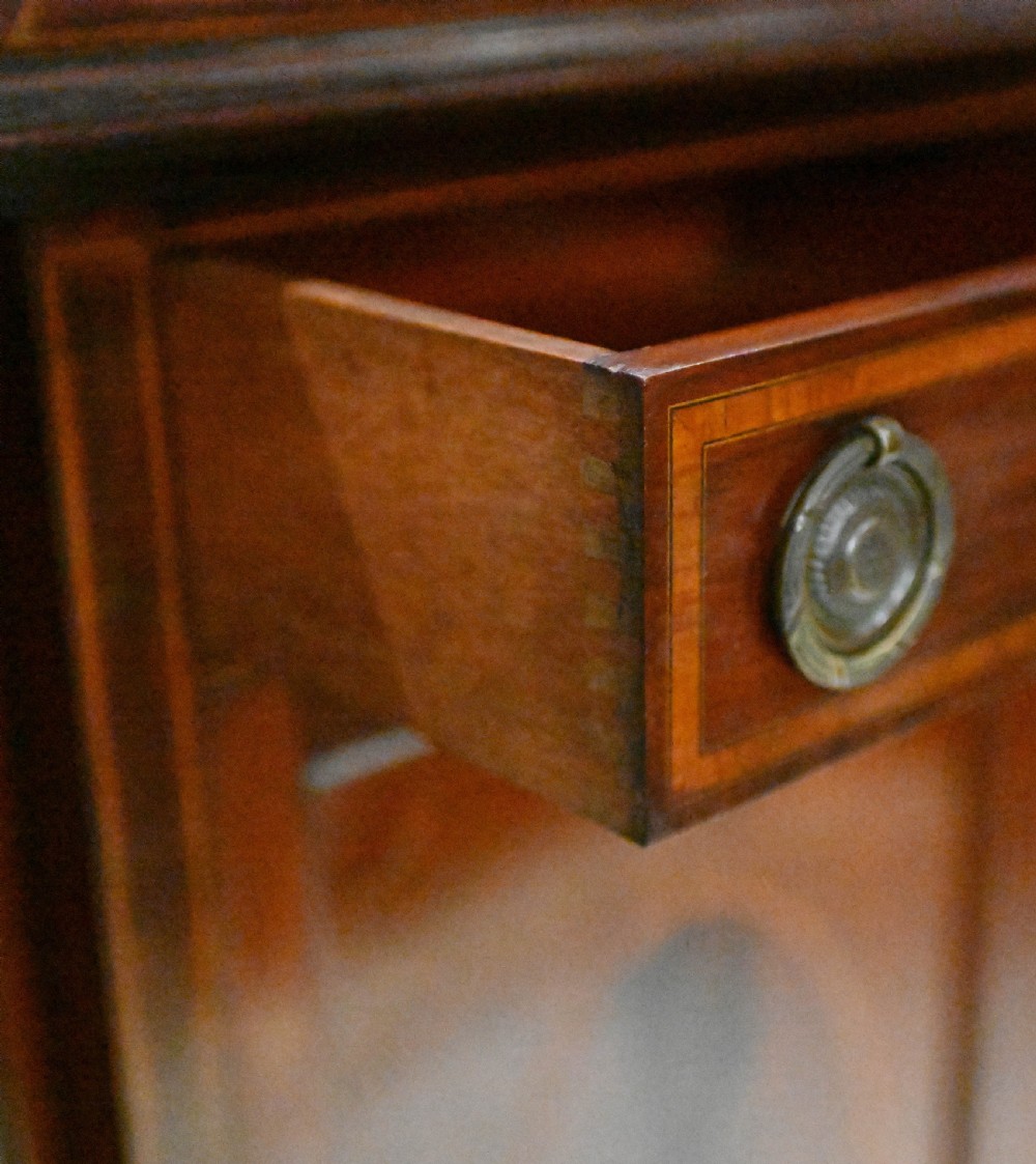 An Edwardian mahogany display cabinet featuring astragal glazed doors flanking a central inlaid cupboard door raised on square tapered legs. View V