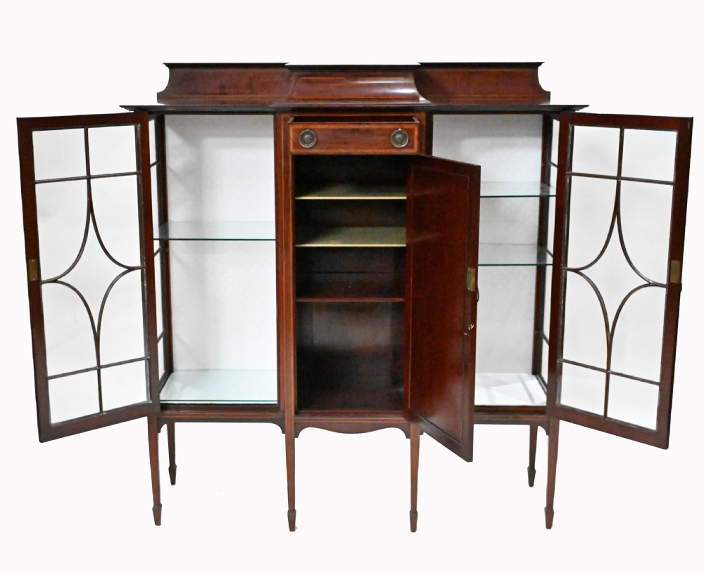 An Edwardian mahogany display cabinet featuring astragal glazed doors flanking a central inlaid cupboard door raised on square tapered legs. View VIII