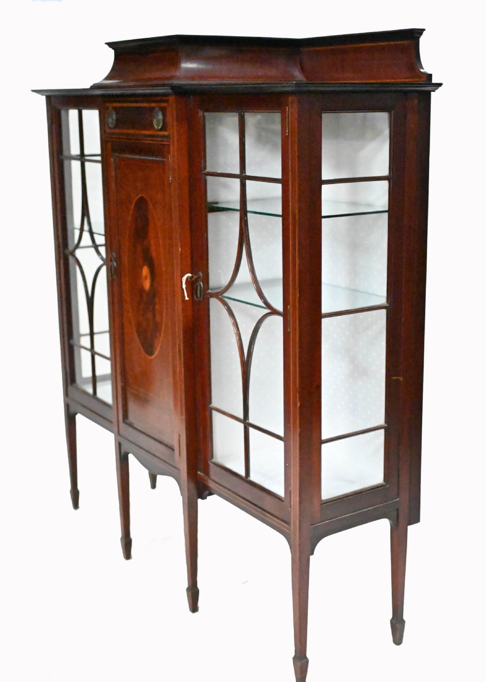 An Edwardian mahogany display cabinet featuring astragal glazed doors flanking a central inlaid cupboard door raised on square tapered legs. View IX