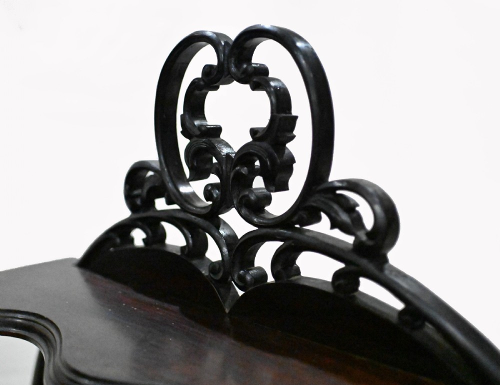 A dark mahogany Art Nouveau display cabinet featuring a pierced cresting, an asymmetrical mirrored superstructure, a single drawer, and a glazed door on slender shaped legs. View VII