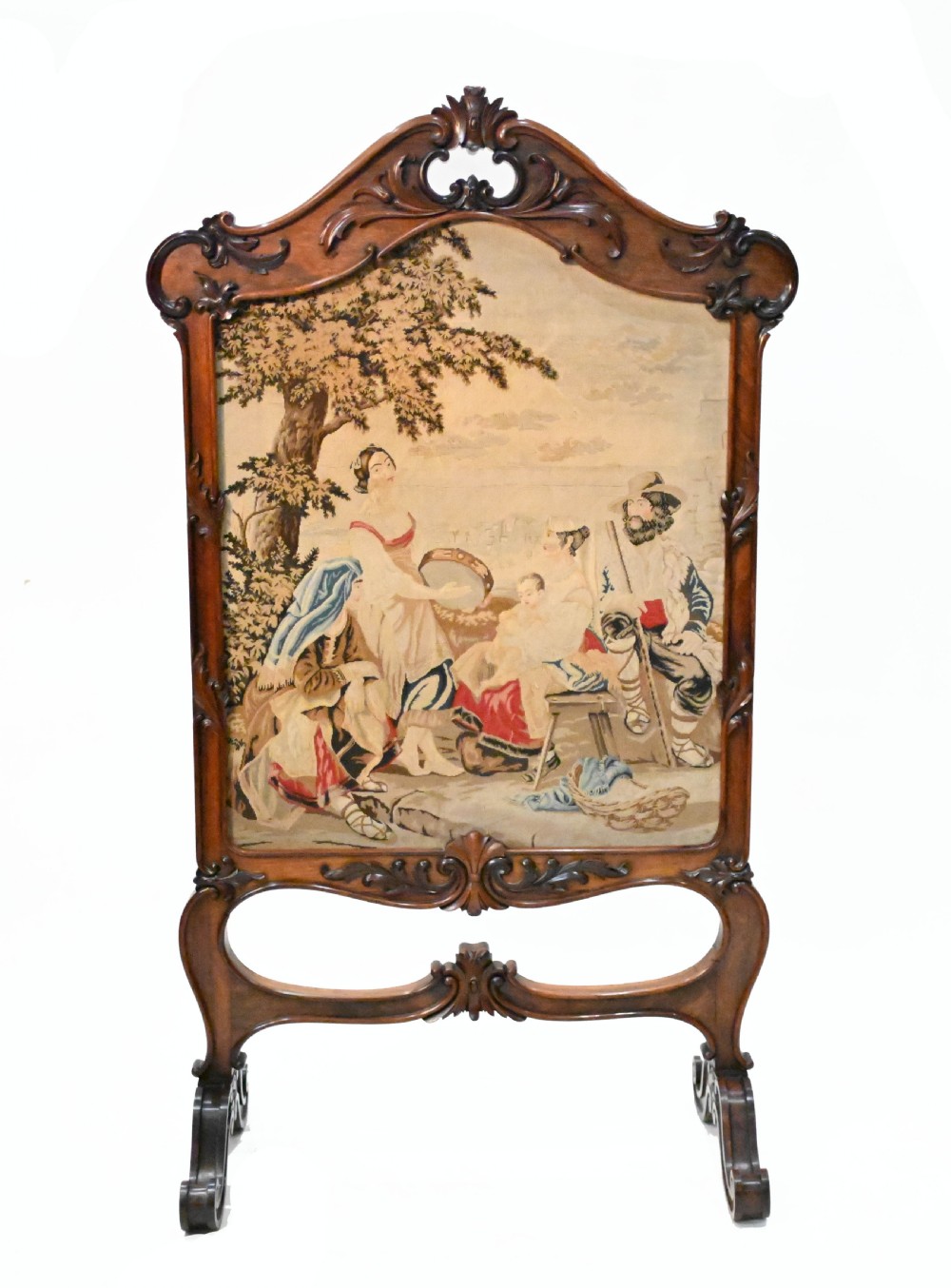An early Victorian carved wooden fire screen featuring a hand-worked needlepoint tapestry of a pastoral scene set within a scrolled frame.