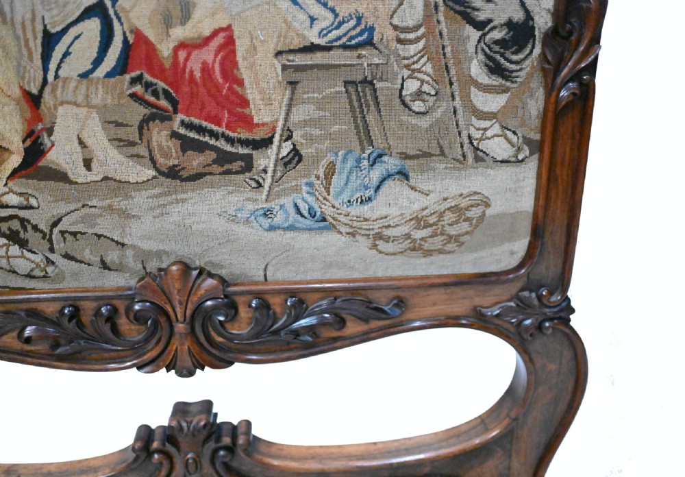 An early Victorian carved wooden fire screen featuring a hand-worked needlepoint tapestry of a pastoral scene set within a scrolled frame. View IV
