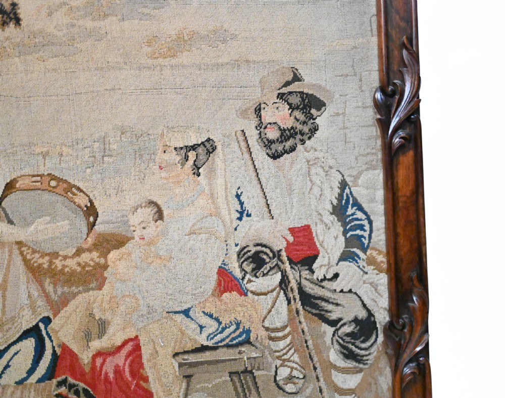 An early Victorian carved wooden fire screen featuring a hand-worked needlepoint tapestry of a pastoral scene set within a scrolled frame. View VI