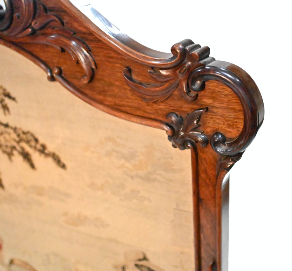 An early Victorian carved wooden fire screen featuring a hand-worked needlepoint tapestry of a pastoral scene set within a scrolled frame. View X