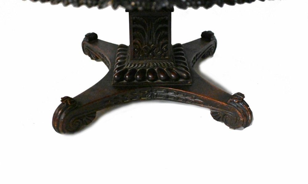 An 1840s Anglo-Indian tilt-top centre table featuring a circular padauk wood top set upon a carved pedestal base. View VI