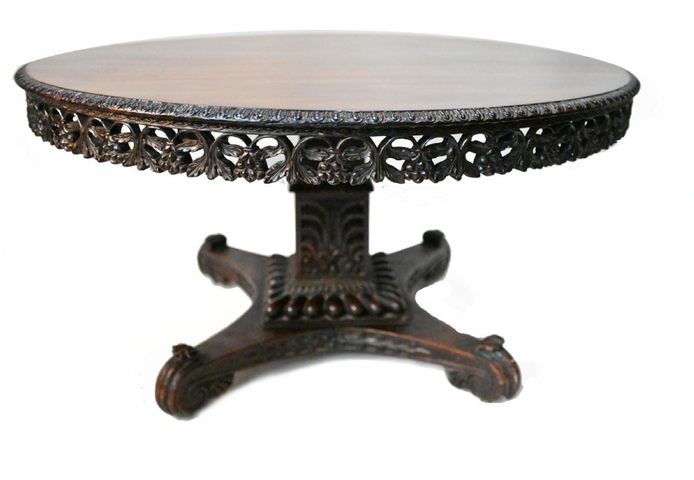 An 1840s Anglo-Indian tilt-top centre table featuring a circular padauk wood top set upon a carved pedestal base. View VII