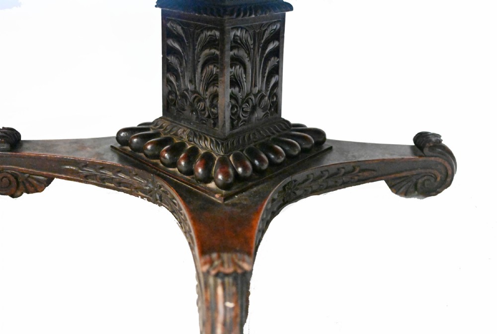 An 1840s Anglo-Indian tilt-top centre table featuring a circular padauk wood top set upon a carved pedestal base. View IX
