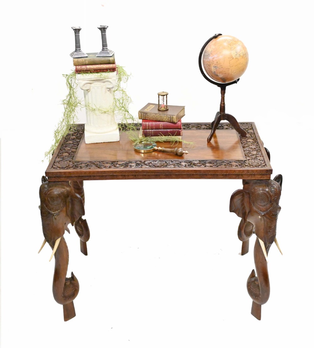 A dark timber rectangular side table featuring a carved foliage border and four legs sculpted as elephant heads with trunks extending to the floor. View II