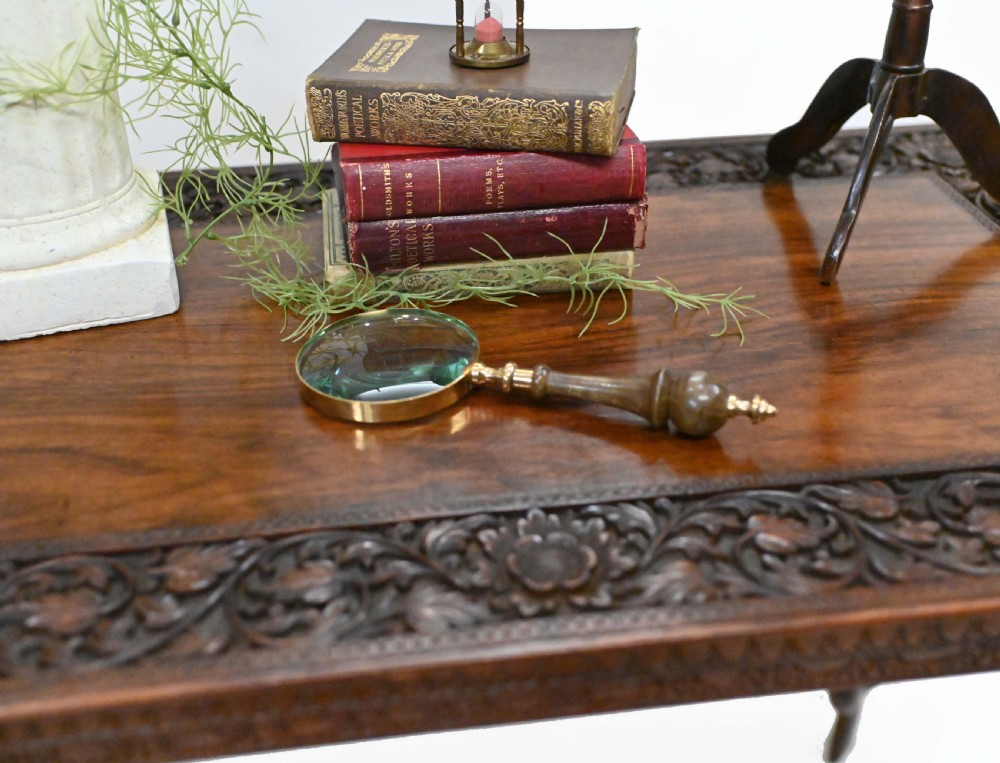 A dark timber rectangular side table featuring a carved foliage border and four legs sculpted as elephant heads with trunks extending to the floor. View III