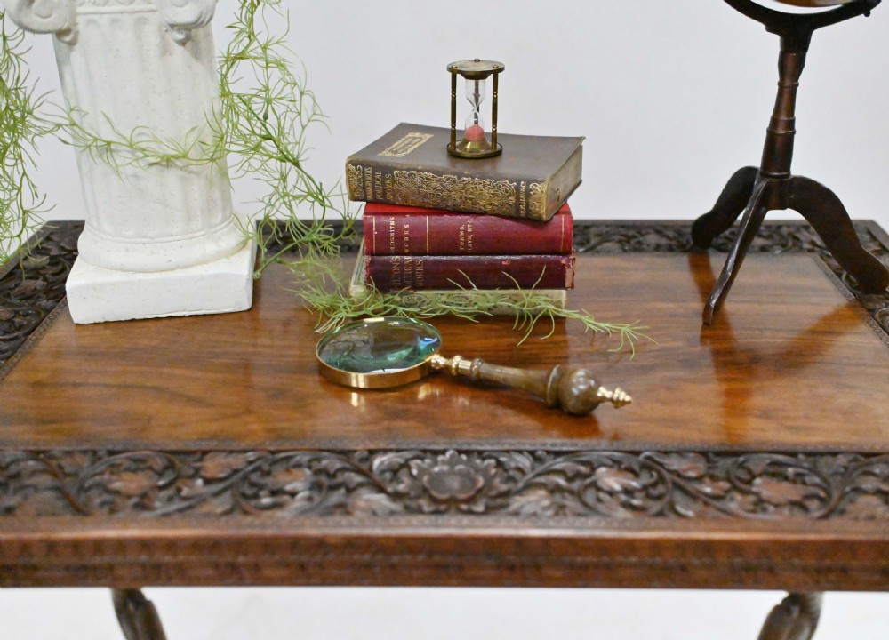 A dark timber rectangular side table featuring a carved foliage border and four legs sculpted as elephant heads with trunks extending to the floor. View VI