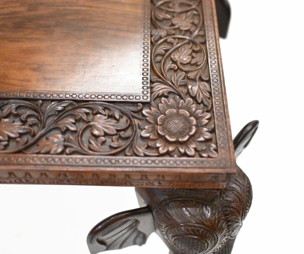 A dark timber rectangular side table featuring a carved foliage border and four legs sculpted as elephant heads with trunks extending to the floor. View IX