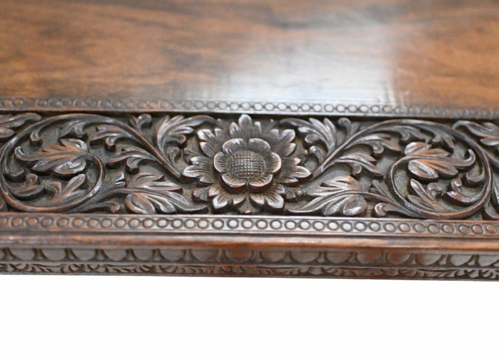 A dark timber rectangular side table featuring a carved foliage border and four legs sculpted as elephant heads with trunks extending to the floor. View XI