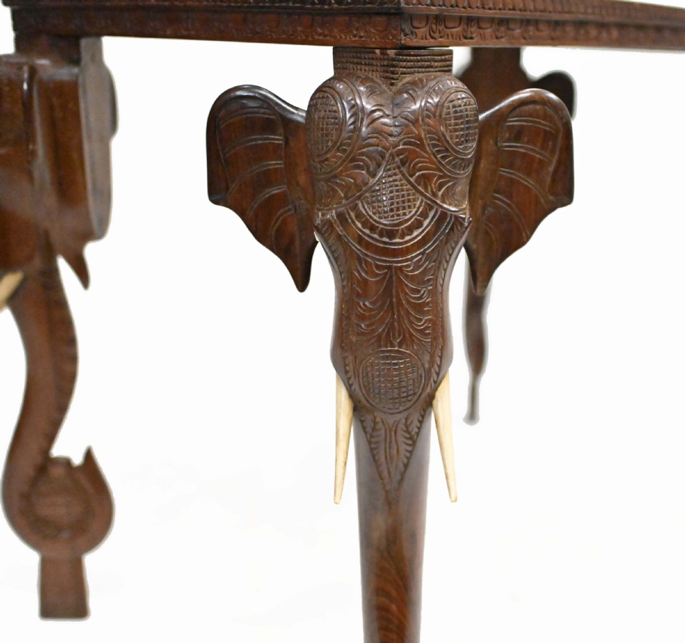 A dark timber rectangular side table featuring a carved foliage border and four legs sculpted as elephant heads with trunks extending to the floor. View XIII