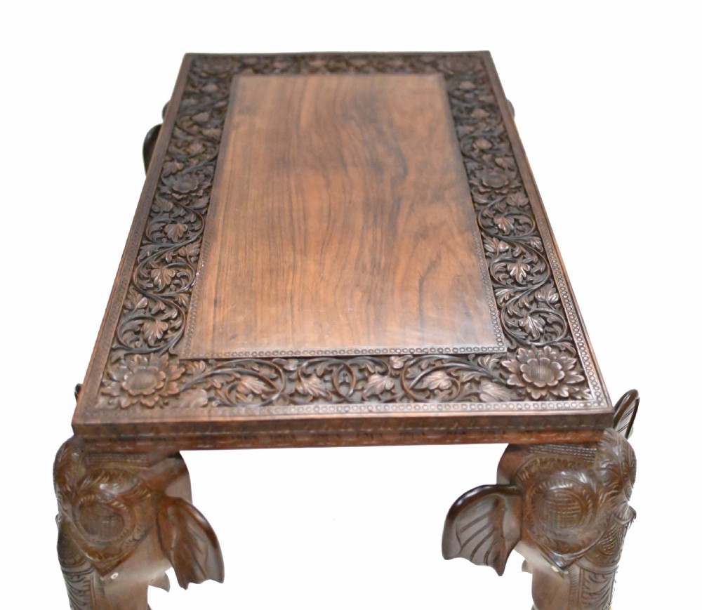 A dark timber rectangular side table featuring a carved foliage border and four legs sculpted as elephant heads with trunks extending to the floor. View XVI