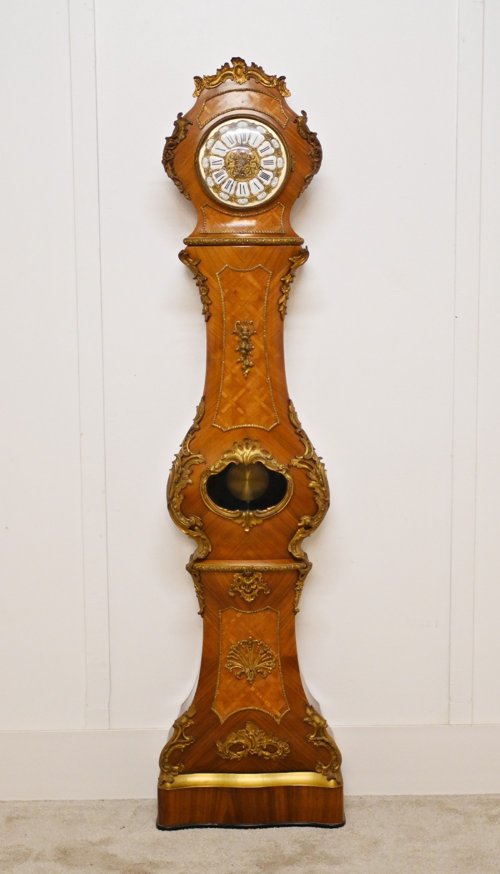A French longcase clock featuring a waisted kingwood veneer body with gilt-bronze mounts and an enamelled dial.