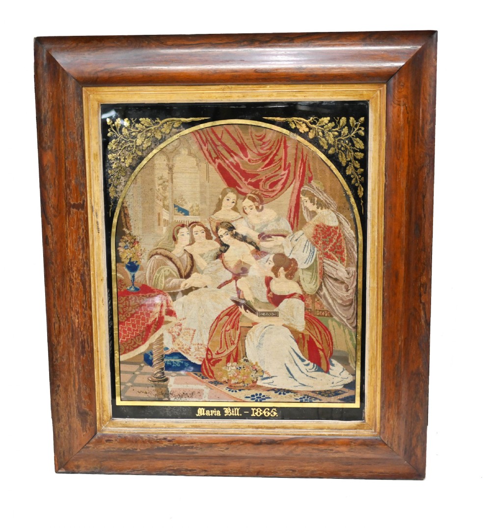 A framed 1865 needlepoint picture depicting a group of courtly maidens in historical dresses, enclosed in an arched gilt black glass mat and polished walnut frame.