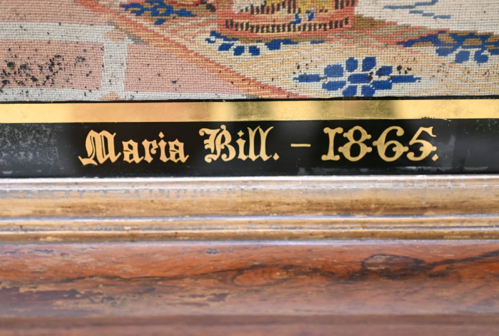 A framed 1865 needlepoint picture depicting a group of courtly maidens in historical dresses, enclosed in an arched gilt black glass mat and polished walnut frame. View V