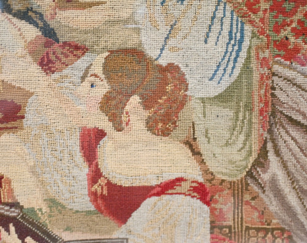 A framed 1865 needlepoint picture depicting a group of courtly maidens in historical dresses, enclosed in an arched gilt black glass mat and polished walnut frame. View VII
