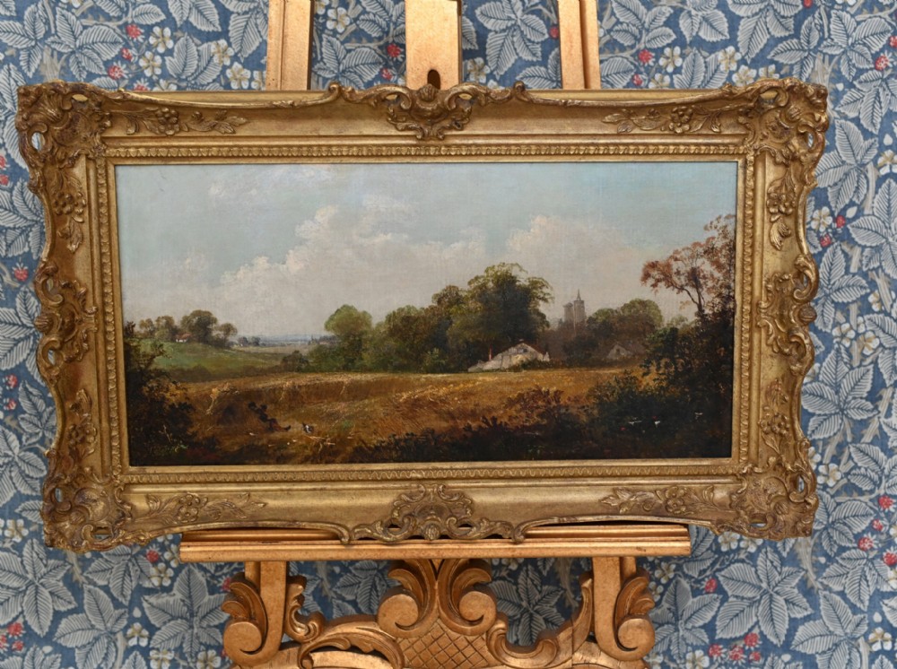 A Victorian oil painting depicting a rural Suffolk landscape with fields and trees, housed in an ornate gold gilded frame.