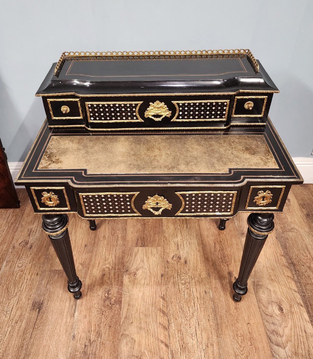 A French Napoleon III ebonised writing desk featuring gilt bronze mounts, brass inlay panels, turned legs, and a raised top superstructure with a brass gallery. View III