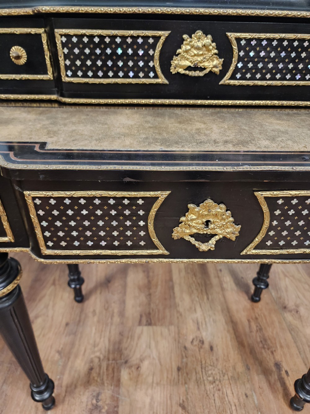 A French Napoleon III ebonised writing desk featuring gilt bronze mounts, brass inlay panels, turned legs, and a raised top superstructure with a brass gallery. View IV