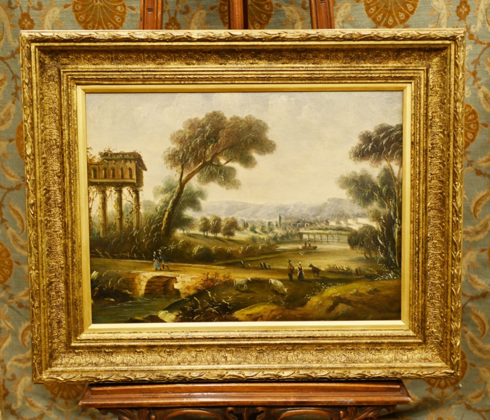 An antique oil painting depicting an Italian pastoral landscape with classical ruins and a stone bridge, housed in an ornate carved gold gilt frame.