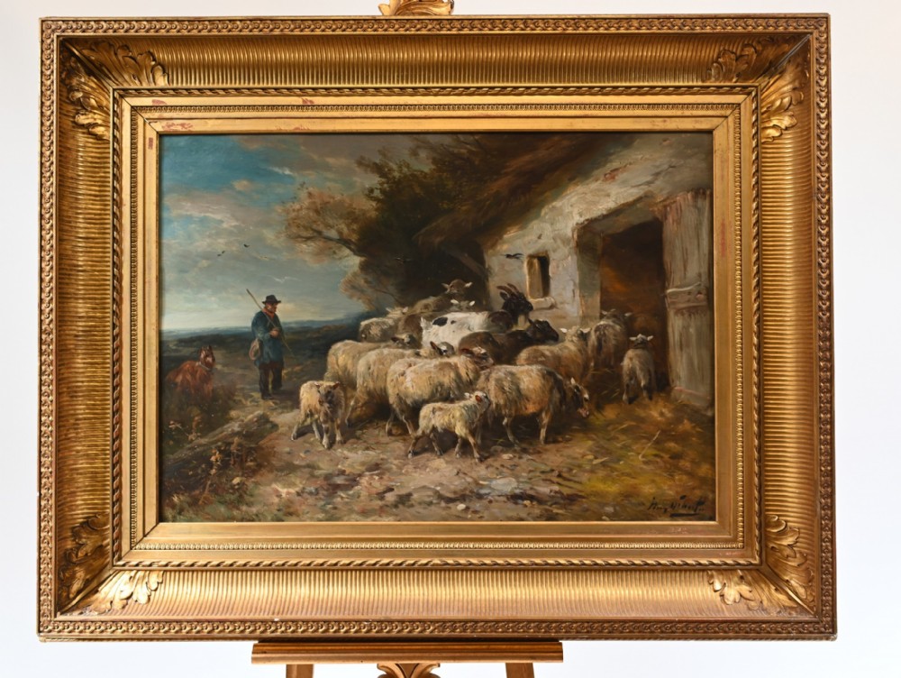 A framed late 19th-century oil painting depicting a shepherd with a flock of sheep and goats outside a rustic whitewashed building.