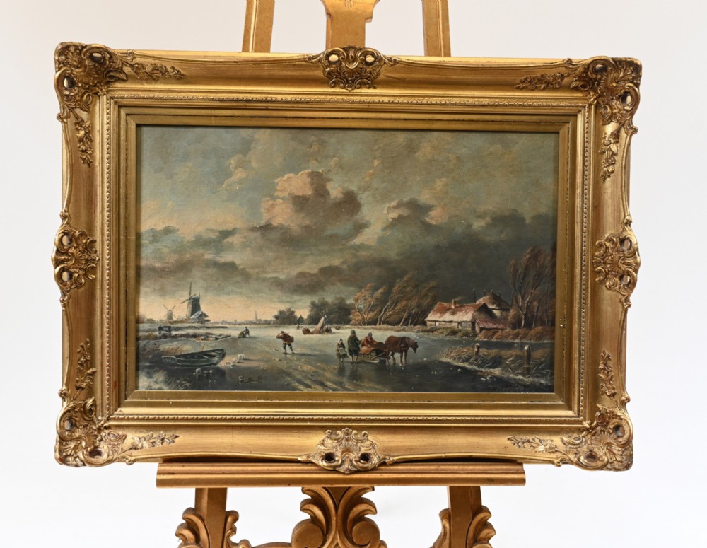 An antique oil painting depicting a frozen Dutch canal scene with figures, windmills, and a horse-drawn sled, framed in an ornate gilded frame.