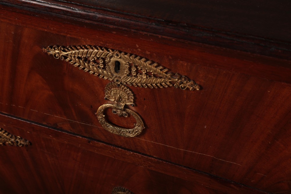 A 19th-century Biedermeier flame mahogany chest of drawers featuring decorative brass escutcheons and drop ring handles. View II