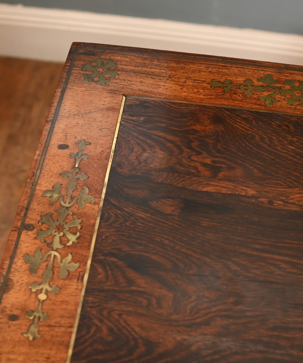 A pair of Regency rosewood and mahogany fold-over card tables featuring brass foliate inlay, central pedestal stems, and splayed quadform legs with brass paw castors. View VII