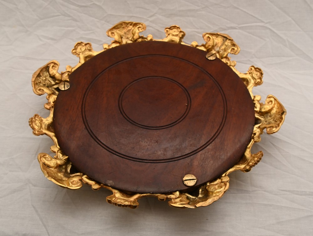 A circular French Rococo style gilt bronze mirrored plateau featuring an ornate scrollwork frame with decorative feet and a foxed mirror insert. View VIII