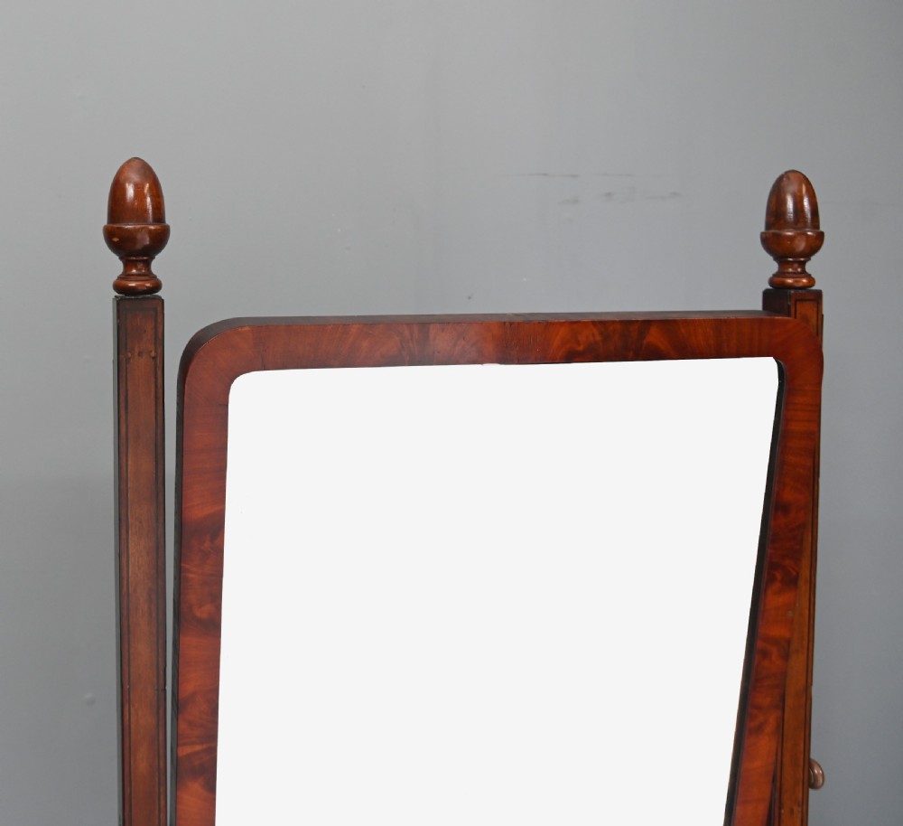 A Regency mahogany cheval mirror featuring an adjustable rectangular mirror plate, turned urn finials, a turned stretcher, and splayed legs on brass castors. View III