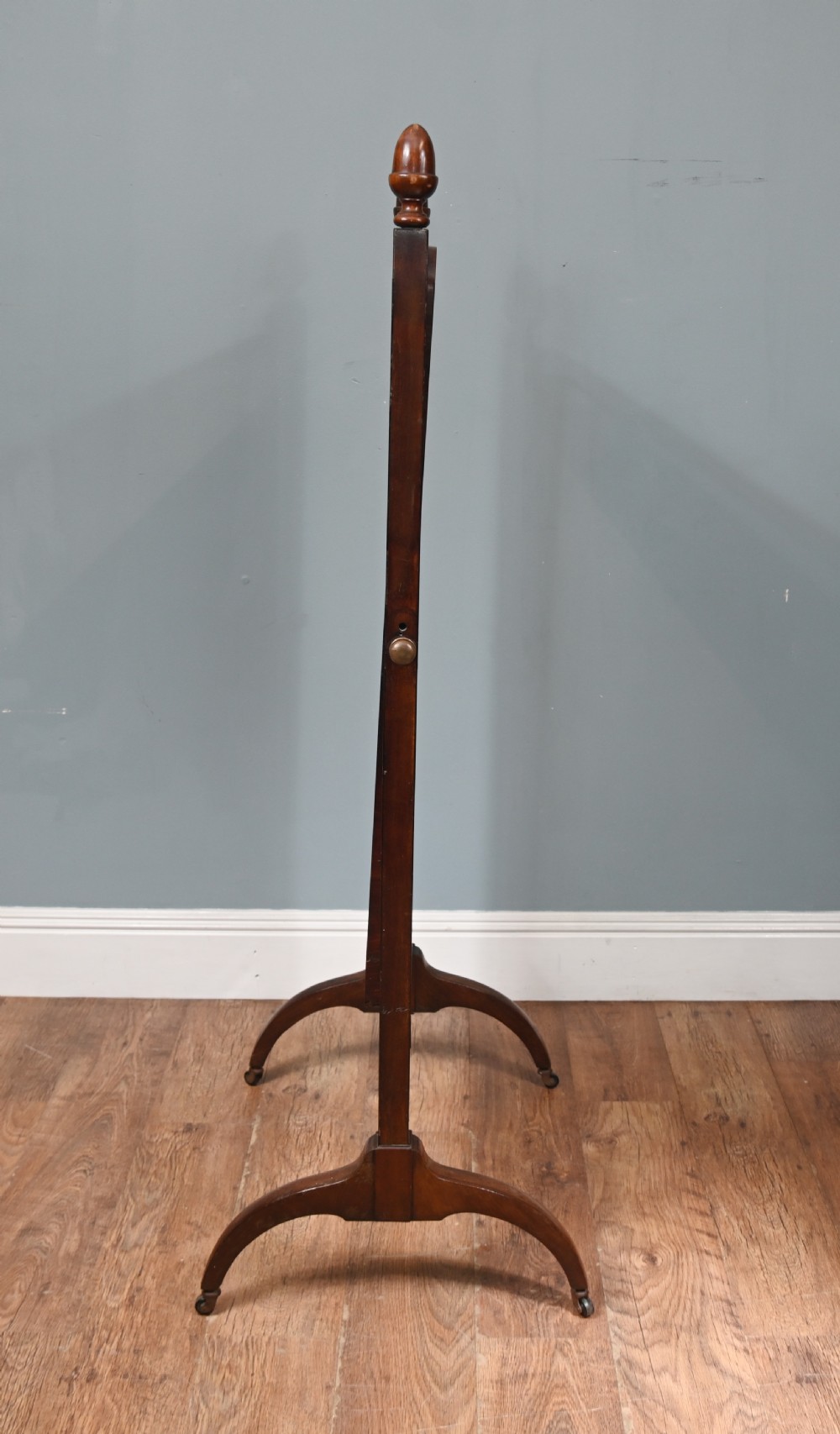 A Regency mahogany cheval mirror featuring an adjustable rectangular mirror plate, turned urn finials, a turned stretcher, and splayed legs on brass castors. View VIII