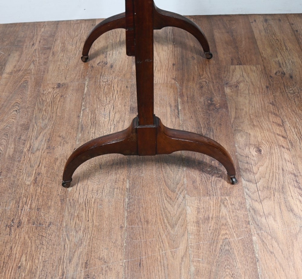 A Regency mahogany cheval mirror featuring an adjustable rectangular mirror plate, turned urn finials, a turned stretcher, and splayed legs on brass castors. View X