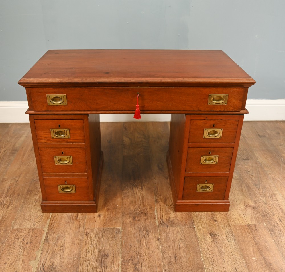 A Victorian mahogany campaign pedestal desk featuring flush brass handles, multiple drawers, and a polished timber surface.