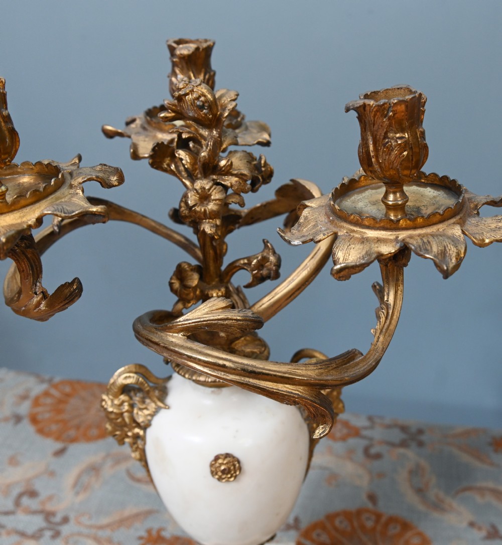 A pair of late 19th-century French Louis XVI Revival gilt bronze and white marble three-arm candelabras featuring urn-shaped bases and floral branch detailing. View II