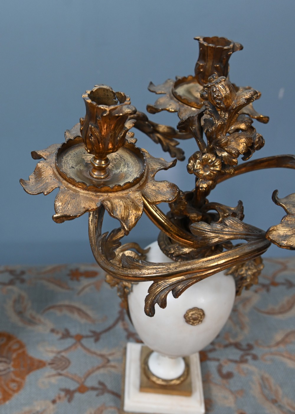 A pair of late 19th-century French Louis XVI Revival gilt bronze and white marble three-arm candelabras featuring urn-shaped bases and floral branch detailing. View V