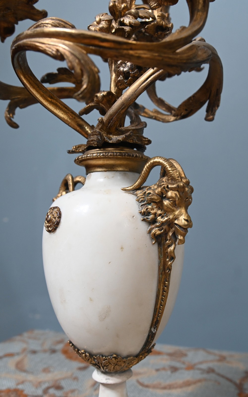 A pair of late 19th-century French Louis XVI Revival gilt bronze and white marble three-arm candelabras featuring urn-shaped bases and floral branch detailing. View X