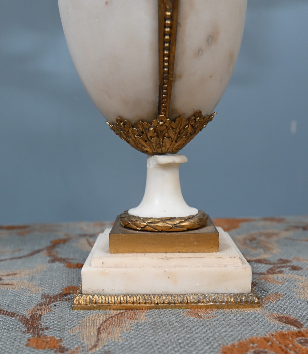 A pair of late 19th-century French Louis XVI Revival gilt bronze and white marble three-arm candelabras featuring urn-shaped bases and floral branch detailing. View XII