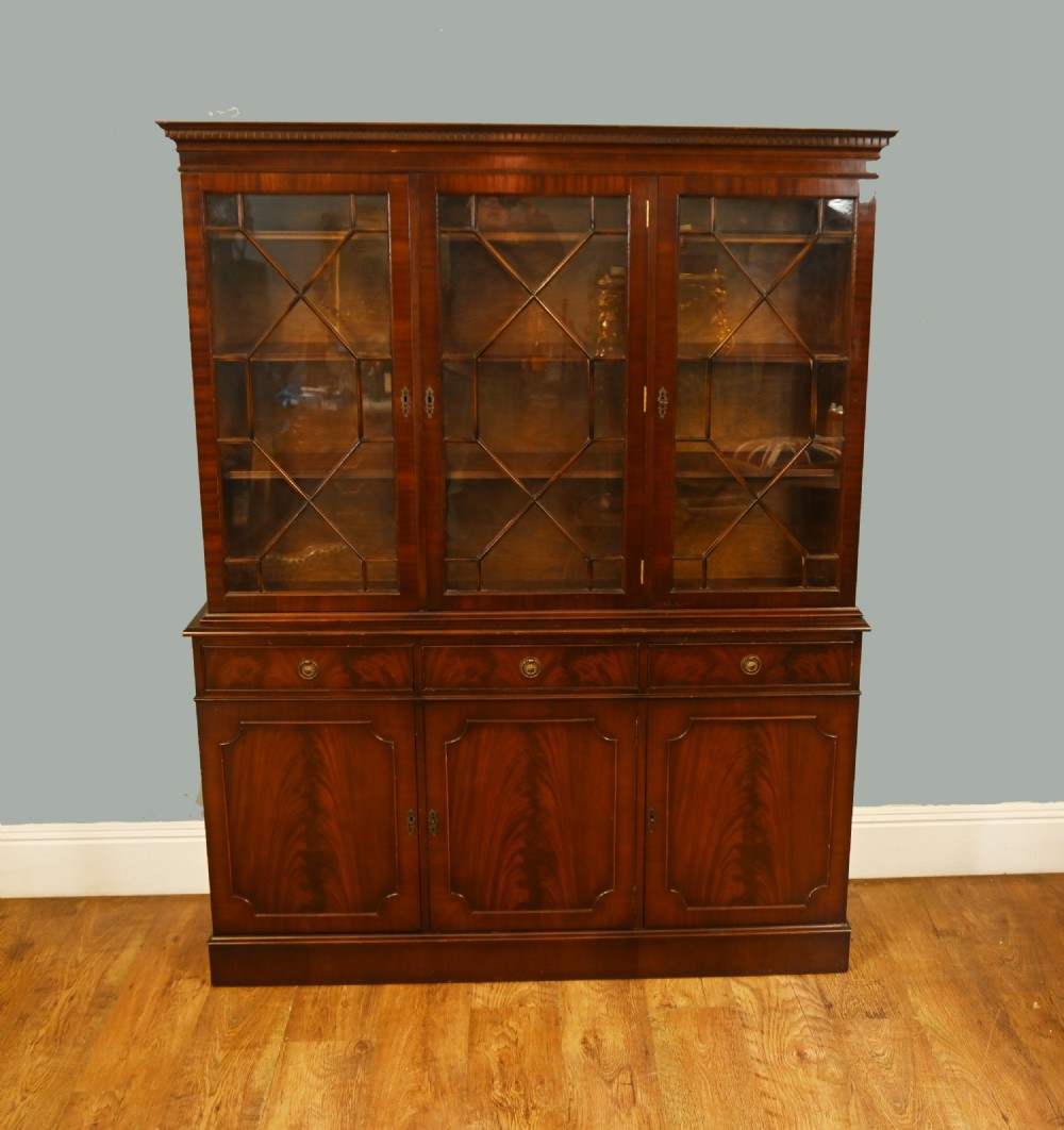A Georgian Revival mahogany bookcase cabinet featuring a three-door astragal glazed upper section above three drawers and flame mahogany cupboard doors. View II
