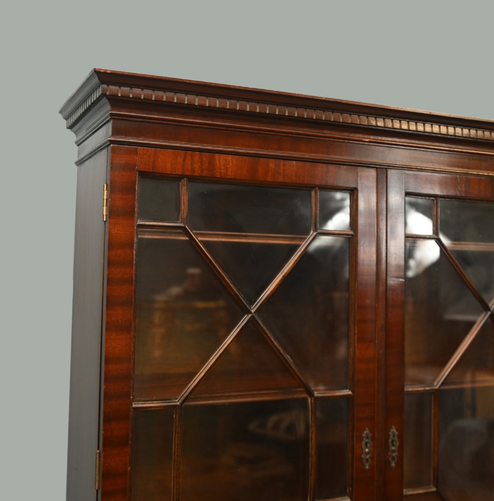 A Georgian Revival mahogany bookcase cabinet featuring a three-door astragal glazed upper section above three drawers and flame mahogany cupboard doors. View V